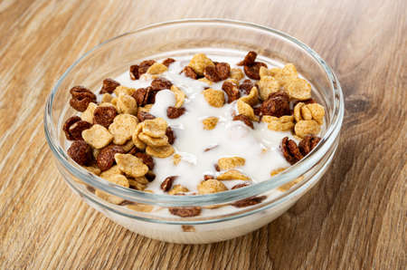 Transparent bowl with cereal grains breakfast with chocolate and caramel and yogurt on wooden table