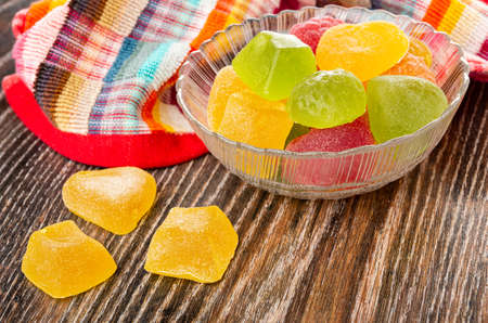 Checkered napkin, multi-colored marmalade of different shapes in transparent glass bowl, marmalade on dark wooden tableの写真素材