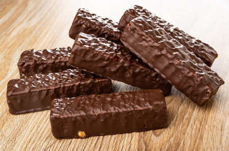 Heap of wafers in chocolate glaze on wooden table