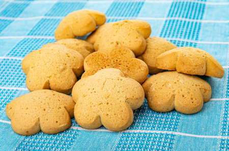 Heap of homemade shortbread cookies on blue checkered tablecloth