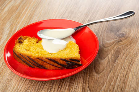 Slice of biscuit in red saucer on brown wooden table