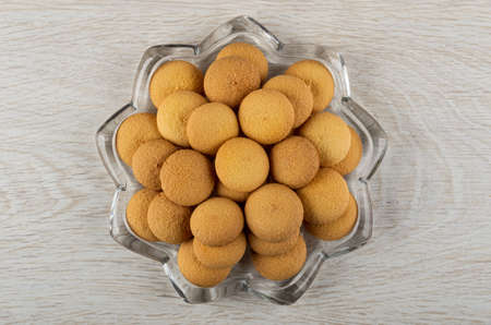 Small round biscuits in transparent plate in shape star on wooden table. Top viewの写真素材