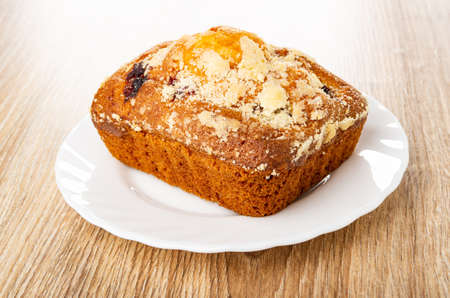 Baked muffin with raisin in white plate on wooden table