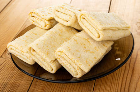 Pancake rolls in brown transparent plate on wooden table