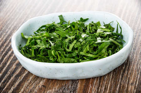 Blue spotted bowl with fresh chopped parsley on dark wooden tableの写真素材