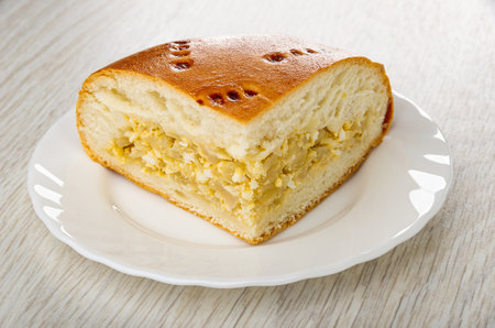 Piece of pie with cabbage and egg in white plate on wooden tableの写真素材