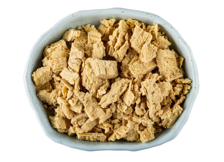 Pieces of peanut halva in light-blue bowl isolated on white background. Top view