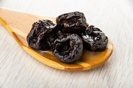 Dried black plums in bamboo spoon on wooden tableの写真素材