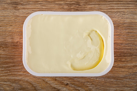 White plastic box with creamy cheese on brown wooden table. Top viewの写真素材