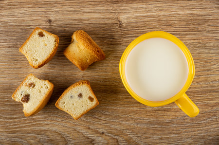 Halves of muffins with raisin, cup of milk on brown wooden table. Top viewの写真素材