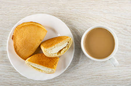 Whole sochen with cottage cheese and  halves of curd envelope in white plate, cup of coffee with...