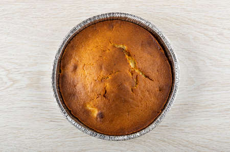 Baked muffin in aluminium mold on wooden table. Top view