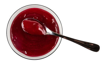 Teaspoon in glass bowl with cherry jam isolated on white background. Top view