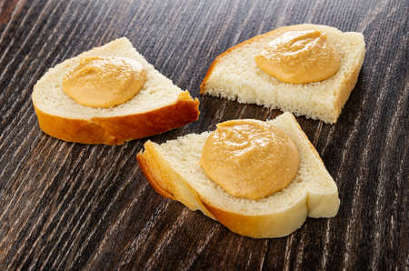 Three small sandwiches with peanut butter on dark wooden table