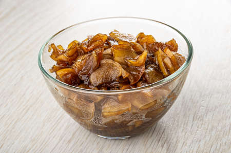 Preserve from slices of apple and cinnamon in transparent bowl on wooden tableの写真素材