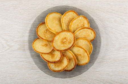 Small homemade pancakes in gray transparent plate on wooden table. Top viewの写真素材