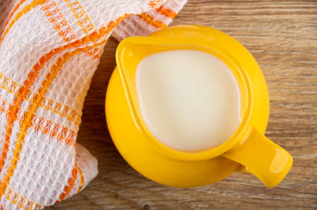 Checkered napkin, yellow glass pitcher with milk on brown wooden table. Top viewの写真素材