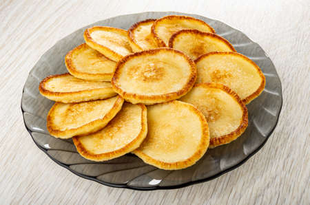 Small homemade pancakes in gray transparent plate on wooden tableの写真素材