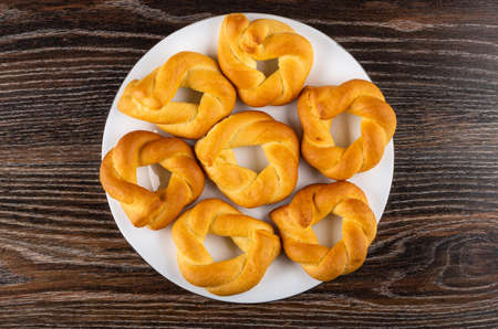 Wicker buns in shape ring in white glass plate on dark wooden table. Top viewの写真素材