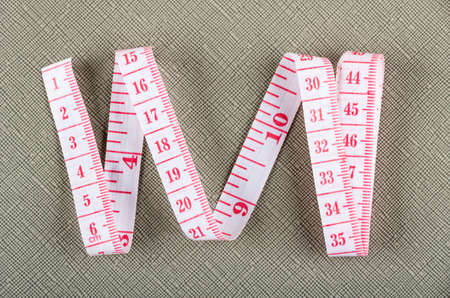 Measure tape with centimeter and inch scale on gray table. Top view
