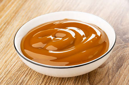 Boiled sweet condensed milk in white bowl on wooden tableの写真素材