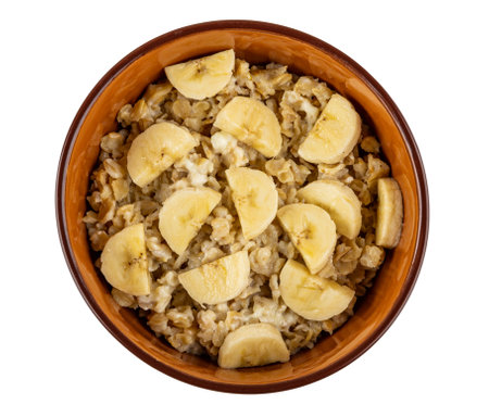 Dairy oatmeal with slices of banana in brown bowl isolated on white background. Top viewの写真素材