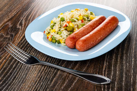 Fried sausages with Hawaiian blend in light-blue plate, fork on dark wooden tableの写真素材