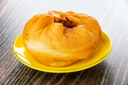 Fried small pie with meat filling (belyash) in yellow saucer on dark wooden tableの写真素材