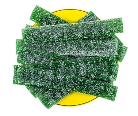 Heap of thin strips of green marmalades in yellow saucer isolated on white background. Top view