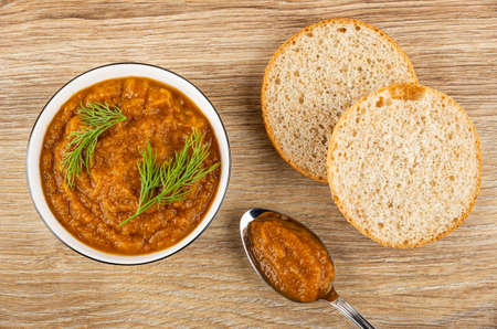 Squash caviar with dill in white glass bowl, slices of round bun, squash caviar in spoon on wooden table. Top viewの写真素材