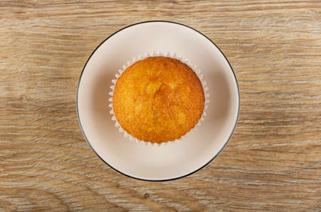 Muffin in paper wrapper in white glass bowl on wooden table. Top viewの写真素材