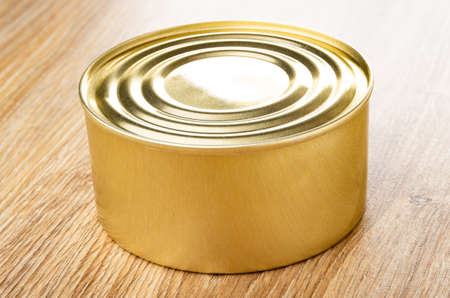 Closed metallic jar with canned food on wooden table