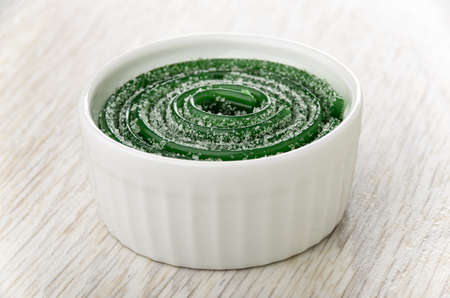 Twisted thin strips of green marmalades in white bowl on wooden table