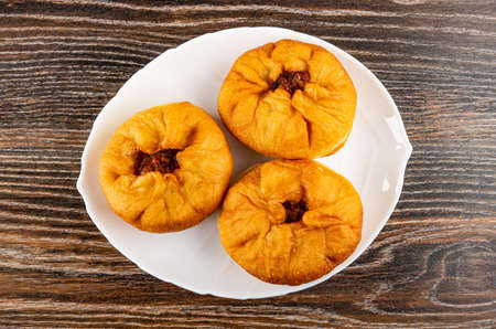 Three fried pies with meat filling (belyash) in white plate on dark wooden table. Top viewの写真素材
