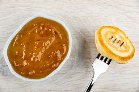 Bowl with lemon jam, homemade small pancake on fork on wooden table. Top viewの写真素材
