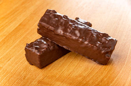 Two glazed chocolate wafers on wooden table