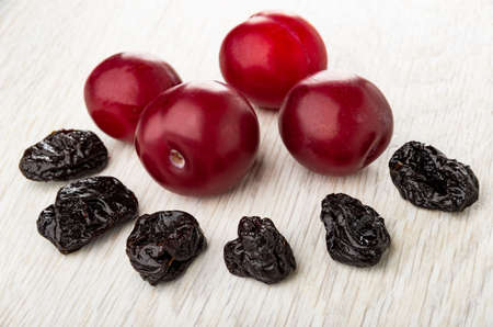 Few ripe plums, few prunes on wooden tableの写真素材