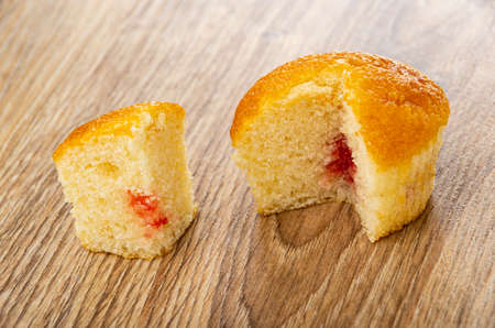 Sections of muffin with jam filling on wooden tableの写真素材
