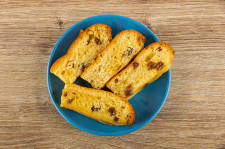 Slices of biscuit cookies with raisin in blue saucer on wooden table. Top viewの写真素材