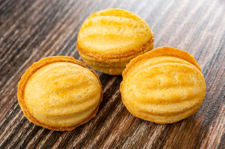 Three cookies in nut shape with condensed milk filling on dark wooden tableの写真素材