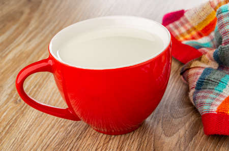 Red glass cup with milk, checkered napkin on brown wooden tableの写真素材