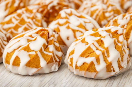 Close up of many cookies in white glaze on wooden table
