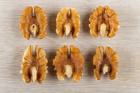 Six of halves of peeled walnuts on wooden table. Top view