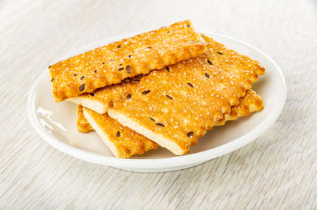 Few sweet cookies with sesame seeds in white saucer on wooden tableの写真素材