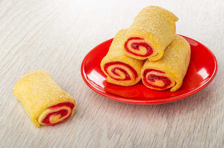 Three rolls with jam in red saucer, one cookie on wooden tableの写真素材