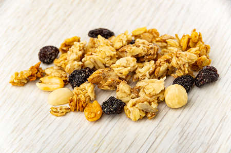 Heap of granola with peanut, hazelnut and raisin on light wooden table