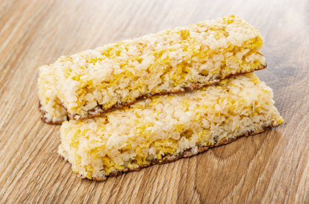 Three granola bar with corn flakes, puffed rice, coconut and chocolate on brown wooden table