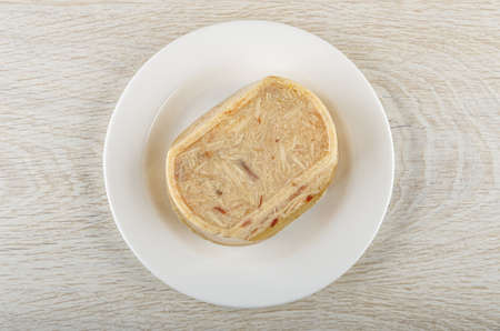 White glass plate with chicken aspic on wooden table. Top view