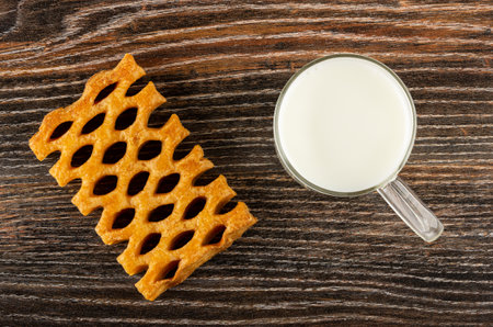 Wicker puff cookie, transparent glass cup with milk on dark wooden table. Top viewの写真素材