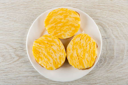 Three sandwiches with butter and cheese in white plate on wooden table. Top viewの写真素材